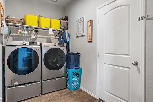 clothes washing area featuring laundry area, baseboards, separate washer and dryer, and wood finished floors