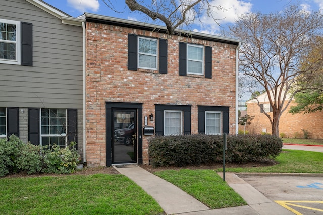 townhome / multi-family property with brick siding and a front lawn