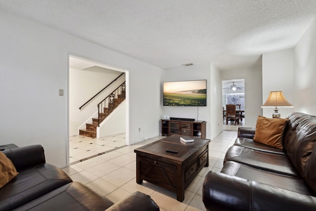 living room with stairs, a textured ceiling, light tile patterned flooring, and visible vents