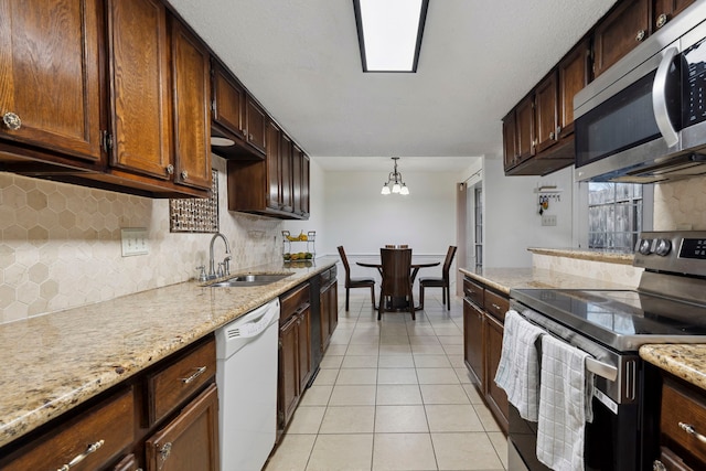 kitchen with light stone counters, a sink, stainless steel appliances, backsplash, and light tile patterned flooring