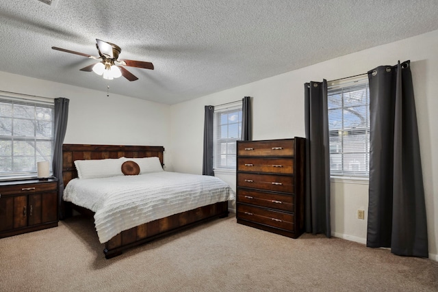 bedroom with multiple windows, ceiling fan, light carpet, and a textured ceiling