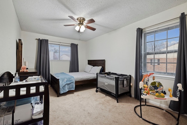 bedroom featuring light carpet, ceiling fan, and a textured ceiling