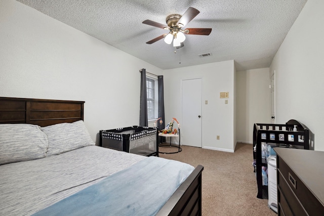 carpeted bedroom with a ceiling fan, baseboards, visible vents, and a textured ceiling