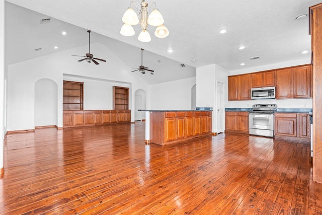 kitchen with arched walkways, dark wood-style floors, appliances with stainless steel finishes, brown cabinets, and open floor plan