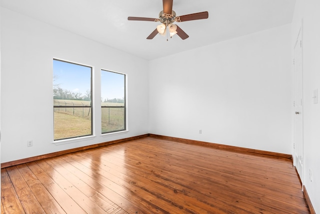 spare room with hardwood / wood-style floors, a ceiling fan, and baseboards