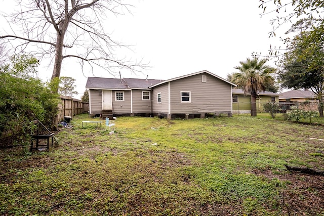 rear view of property featuring entry steps, a fenced backyard, and a lawn