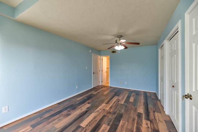 unfurnished bedroom with dark wood-style flooring, visible vents, a ceiling fan, a textured ceiling, and baseboards