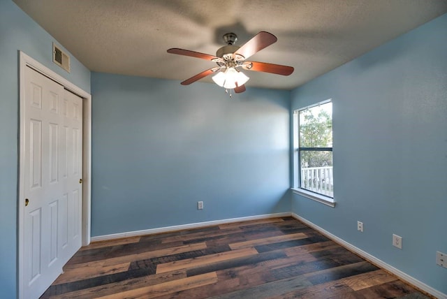 spare room with a textured ceiling, wood finished floors, visible vents, and baseboards