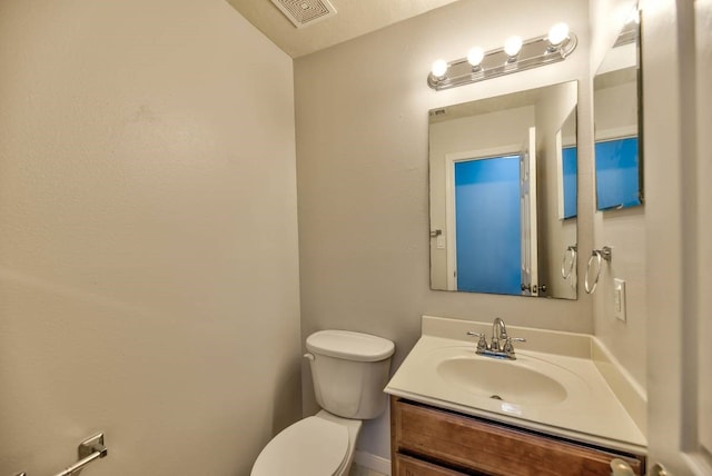 half bath featuring visible vents, vanity, and toilet