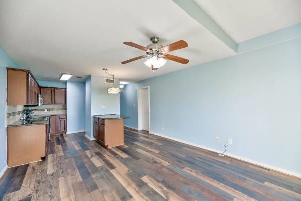 kitchen featuring tasteful backsplash, baseboards, dark wood finished floors, a ceiling fan, and hanging light fixtures