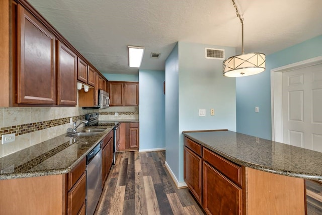 kitchen with stainless steel appliances, visible vents, dark wood-style floors, and tasteful backsplash