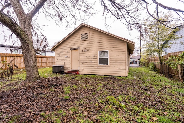 back of property with entry steps, a fenced backyard, and central AC