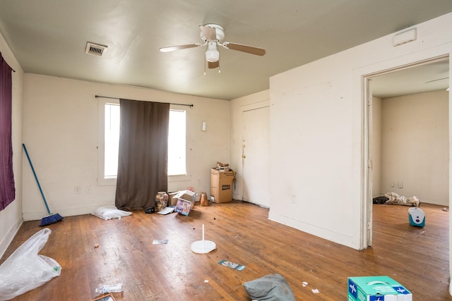 interior space with a ceiling fan, visible vents, and wood finished floors