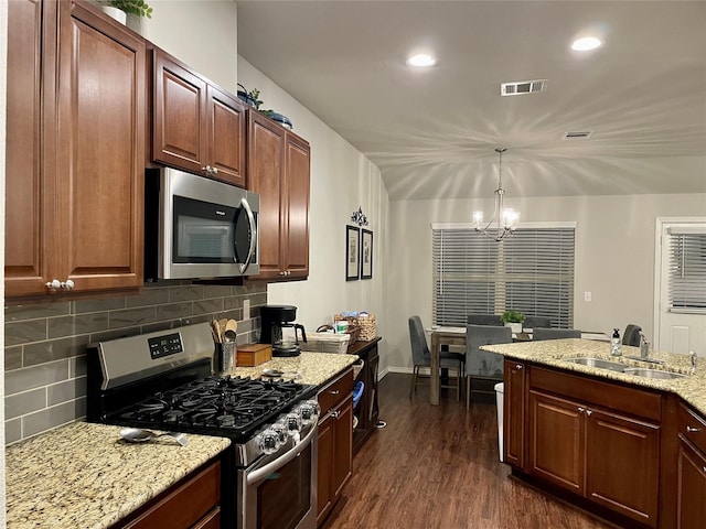 kitchen with stainless steel appliances, a sink, visible vents, backsplash, and dark wood finished floors