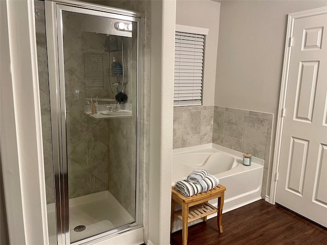 bathroom with a bath, a shower stall, and wood finished floors