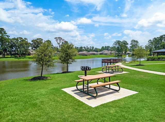 view of property's community with a water view and a lawn