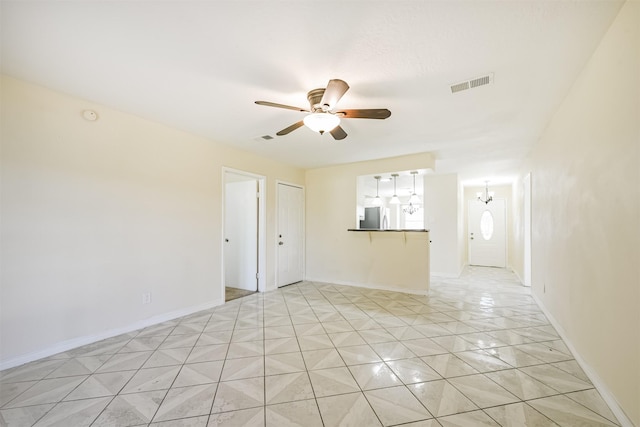 unfurnished room with ceiling fan with notable chandelier, light tile patterned floors, visible vents, and baseboards