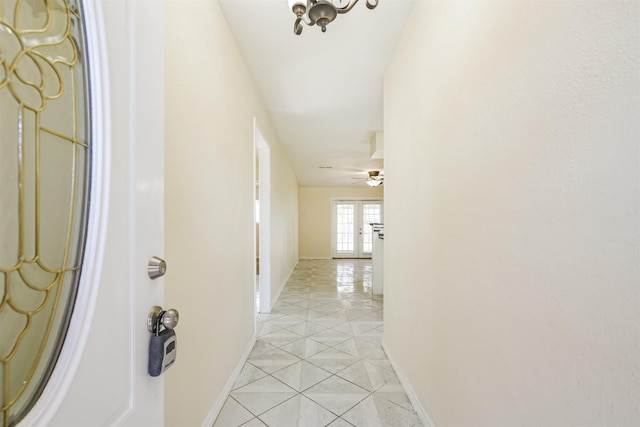 hall featuring light tile patterned floors and baseboards