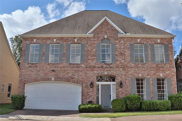 view of front of house with a shingled roof, brick siding, and an attached garage