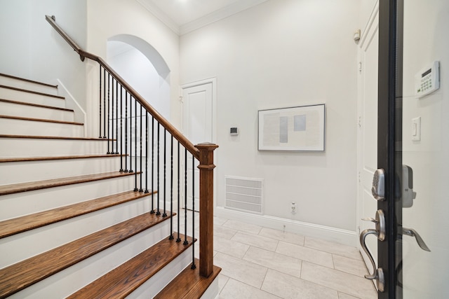 entryway with arched walkways, light tile patterned floors, visible vents, ornamental molding, and baseboards