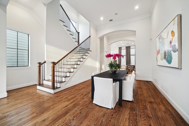 dining area featuring arched walkways, wood finished floors, and baseboards