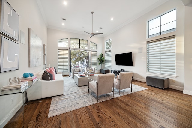 living room with ornamental molding, wood finished floors, visible vents, and baseboards