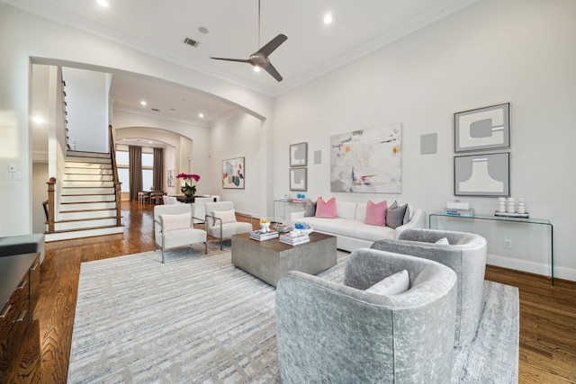 living area featuring arched walkways, visible vents, stairway, and wood finished floors