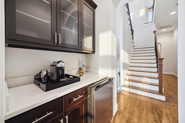 bar with baseboards, visible vents, dishwasher, stairway, and light wood-style floors