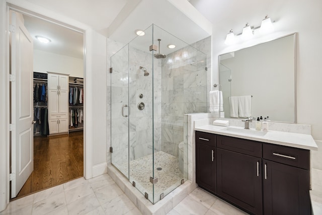 bathroom with marble finish floor, a spacious closet, a shower stall, and vanity