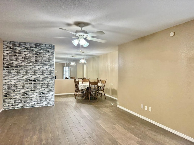 dining room with baseboards, a textured ceiling, a ceiling fan, and wood finished floors