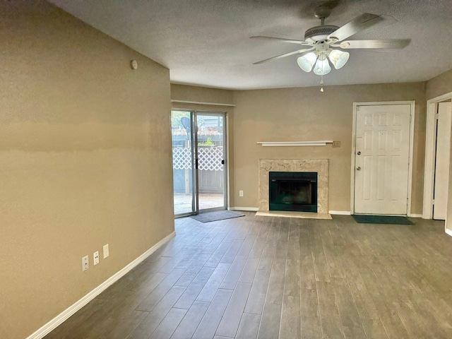 unfurnished living room with a textured ceiling, a premium fireplace, wood finished floors, and baseboards