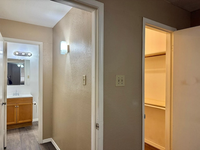 hall featuring baseboards, dark wood finished floors, and a sink