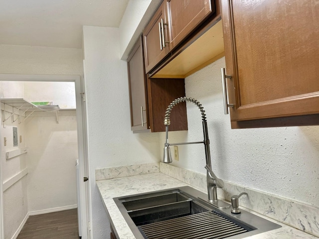 kitchen featuring a sink, baseboards, light countertops, dark wood-style floors, and brown cabinetry