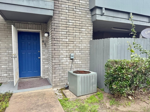 doorway to property with cooling unit and brick siding