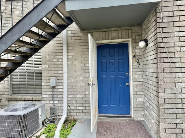 entrance to property featuring cooling unit and brick siding