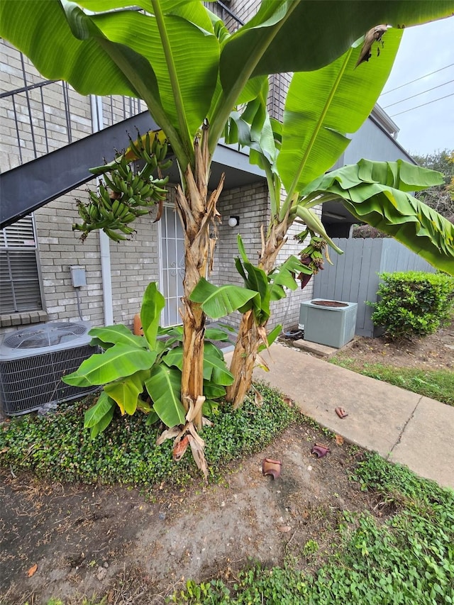 exterior space with brick siding, cooling unit, and fence