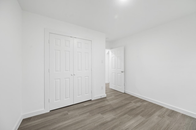 unfurnished bedroom featuring a closet, baseboards, and wood finished floors