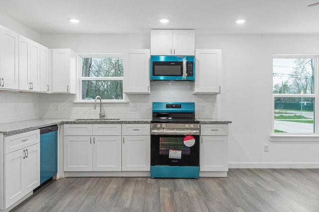 kitchen featuring light stone counters, stainless steel appliances, a sink, light wood-style floors, and white cabinets