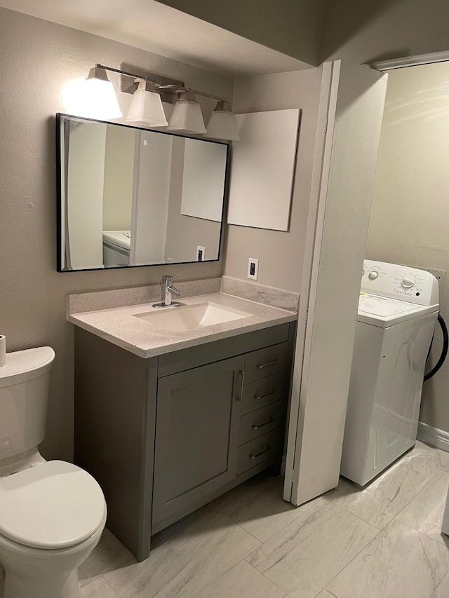 bathroom with toilet, washer / dryer, marble finish floor, and vanity