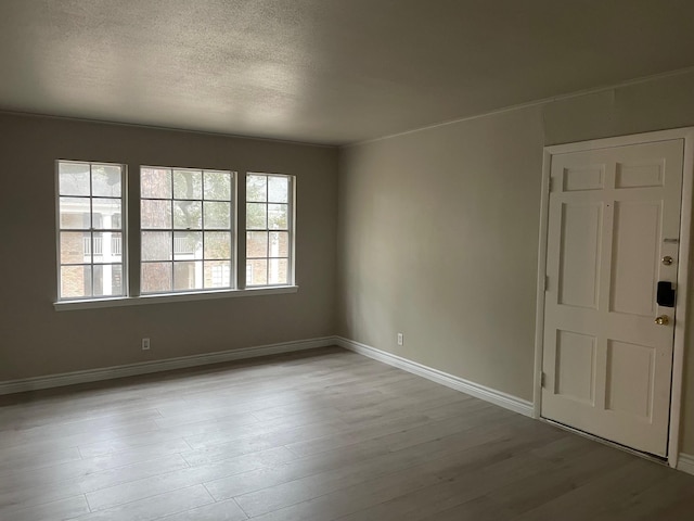 spare room with a textured ceiling, baseboards, and wood finished floors