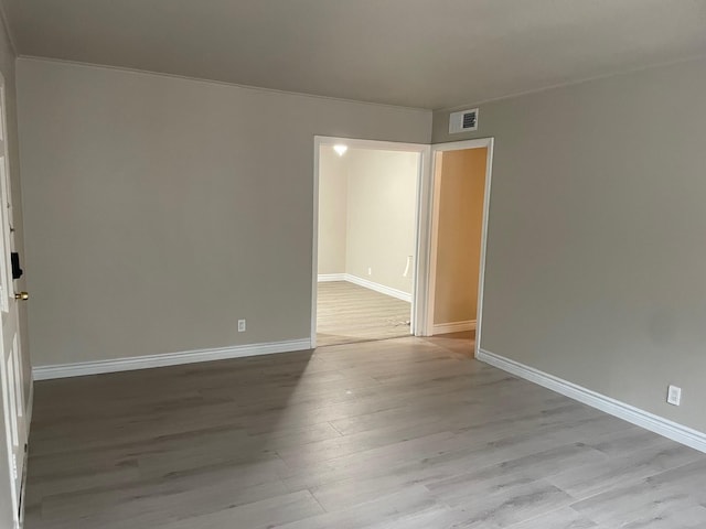 empty room featuring visible vents, baseboards, and wood finished floors