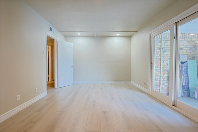spare room with a healthy amount of sunlight, light wood finished floors, and visible vents