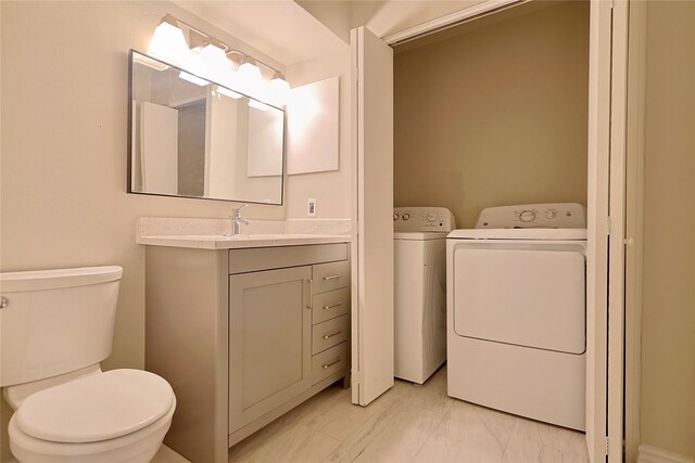 half bath featuring vanity, washing machine and dryer, toilet, and marble finish floor