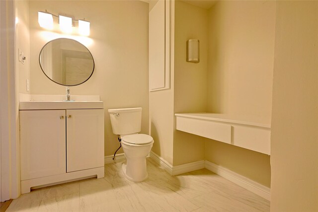 bathroom with baseboards, vanity, and toilet