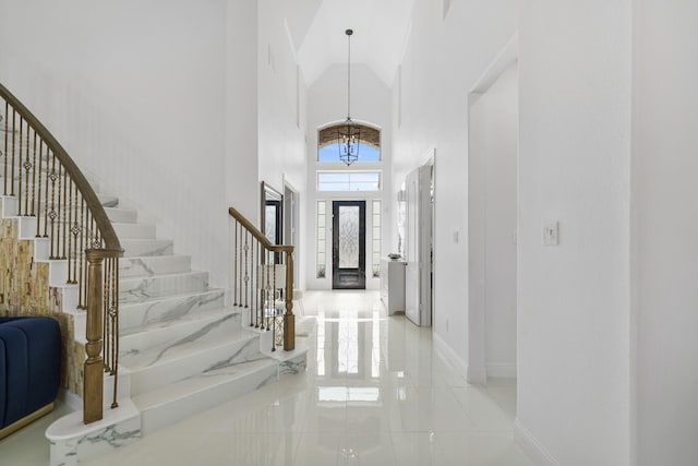 foyer entrance with baseboards, stairs, and high vaulted ceiling