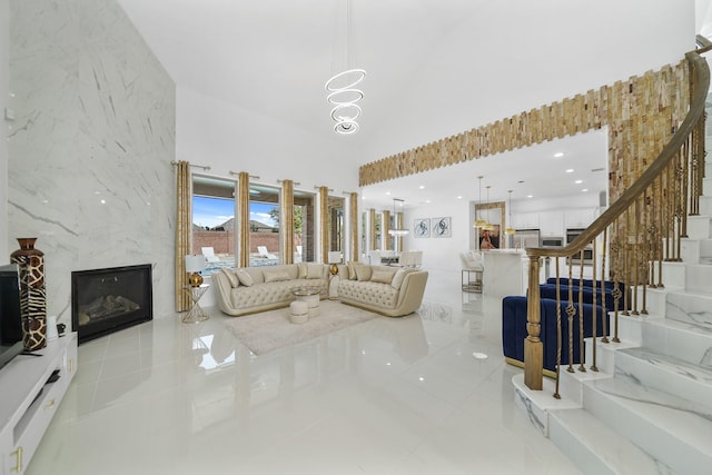 living room featuring a high ceiling, a fireplace, stairway, and recessed lighting