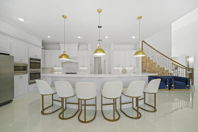 kitchen featuring a kitchen bar, white cabinetry, stainless steel appliances, and backsplash