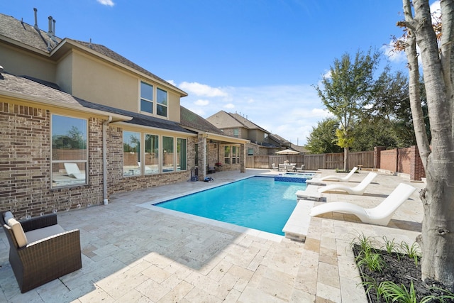 view of swimming pool with a fenced backyard, a pool with connected hot tub, and a patio