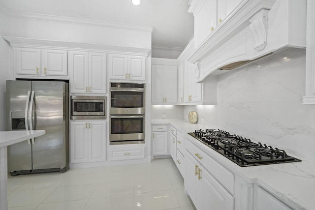 kitchen featuring white cabinets, decorative backsplash, stainless steel appliances, crown molding, and premium range hood