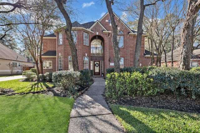 tudor-style house featuring a front lawn and brick siding